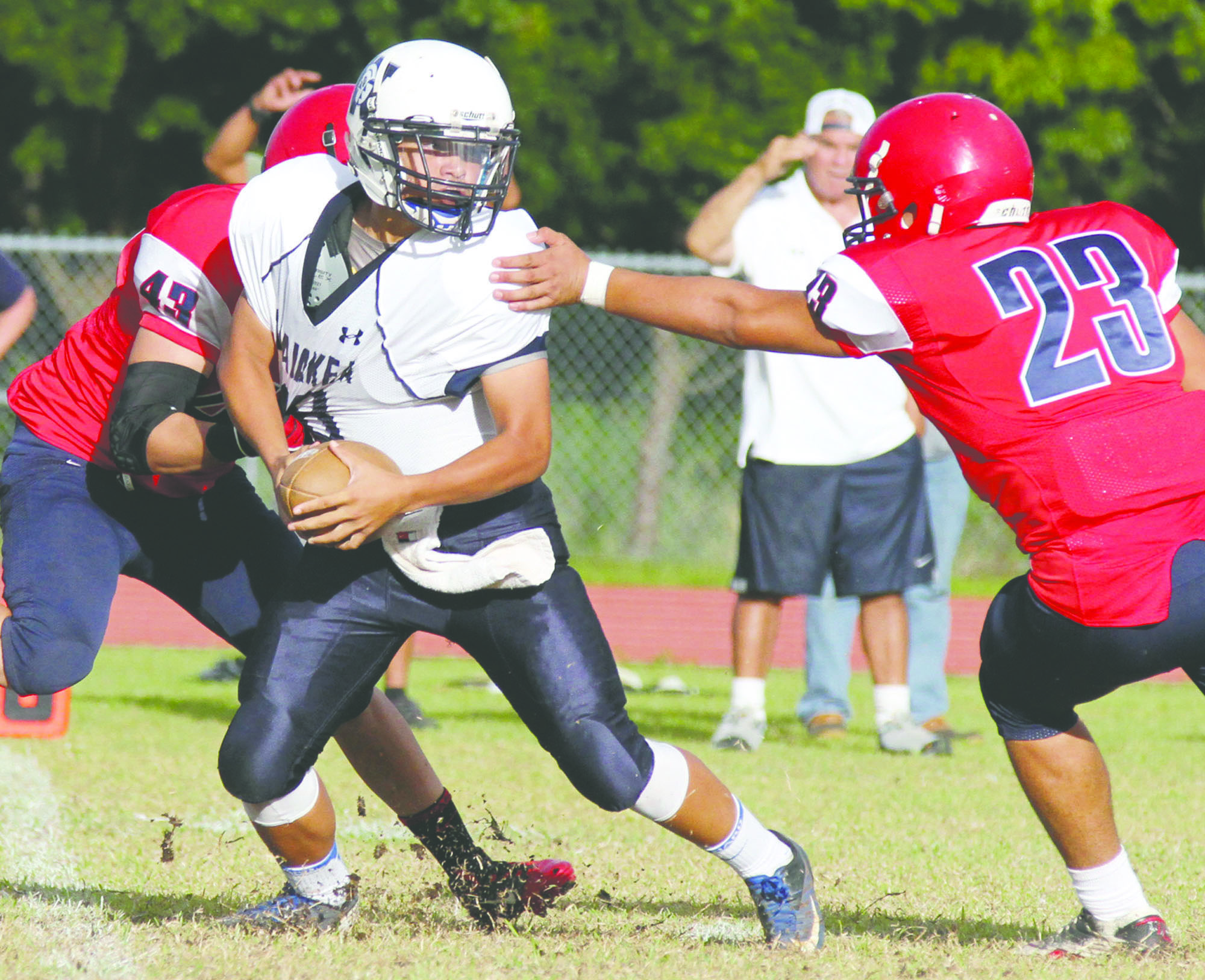 TIM WRIGHT/Tribune-Herald Waiakea's Bryce Felipe tries to avoid pressure from Keaau's Tihoti Tadeo (23) and Justin Hong on Saturday during the Warriors' 13-7 victory.